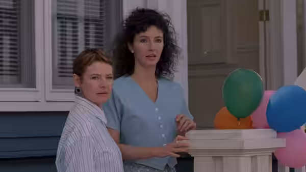 Susan Buckman (Harley Jane Kozak) and Karen Buckman (Mary Steenburgen) stand beside balloons outside a house
