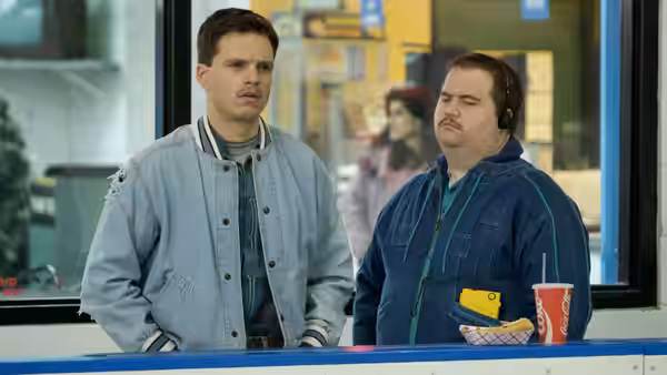 Jeff (Sebastian Stan) and Shawn (Paul Walter Hauser) stand beside a rink-side counter