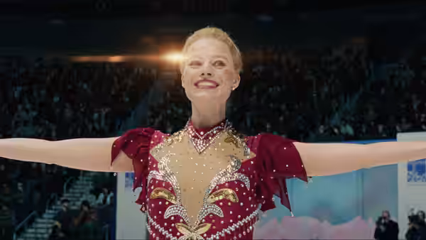 Tonya (Margot Robbie) smiles with arms outstretched on the ice before a crowded arena
