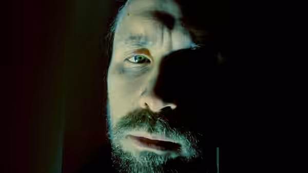 Close-up of Richard (Paddy Considine) with a bruised face in dim light