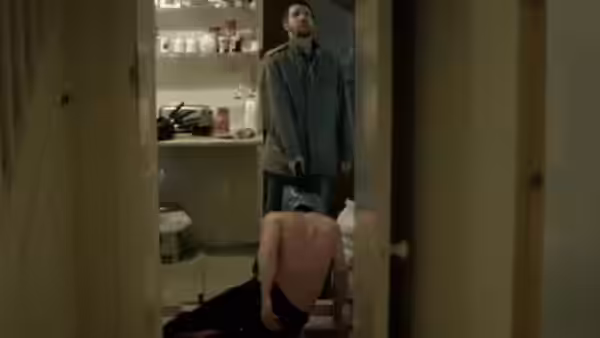 Richard (Paddy Considine) holds a handgun while a bound man kneels on the floor