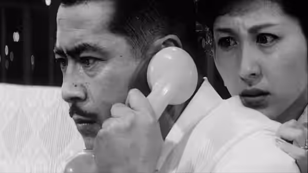 Kingo Gondo (Toshirō Mifune) on the telephone with Reiko (Kyōko Kagawa) beside him