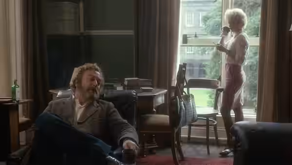 Frank (Michael Caine) seated with a drink while Rita (Julie Walters) stands by a window