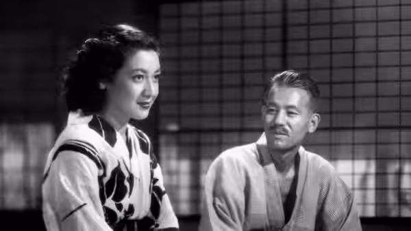 woman in floral kimono sits facing a man in plain robe on tatami