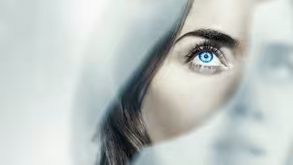 A woman's blue eye gazes amid soft blurred faces