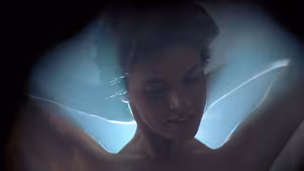 A young woman looks down in a glowing pool