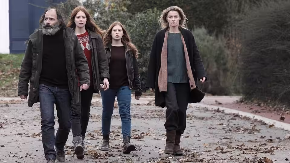 Four adults walking together on a path covered with fallen leaves
