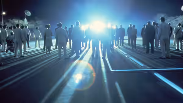 People walking along a runway towards intense bright lights