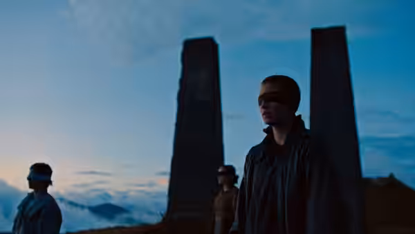 blindfolded people standing near large stone pillars under a blue sky