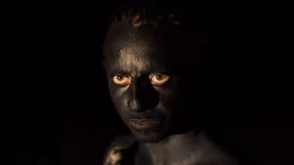 close-up of a face covered in black paint with glowing eyes