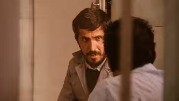 Hossain Sabzian peering through a doorway at another man