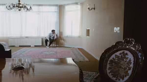 Man sitting on a chair in a large empty room with windows