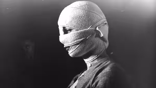 A woman with her head and face wrapped in bandages turns to the side