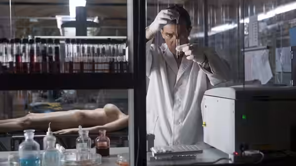 Dr. Robert Ledgard (Antonio Banderas) examines a sample in his laboratory beside a motionless body