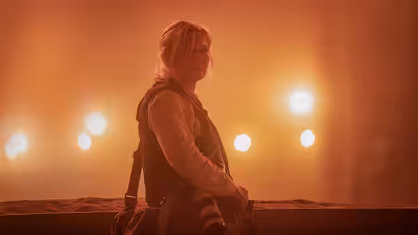Lee (Kirsten Dunst) sitting on a ledge holding a camera in smoke