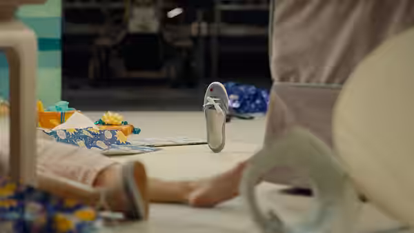 A sneaker floats above a picnic blanket beside people lying on the ground