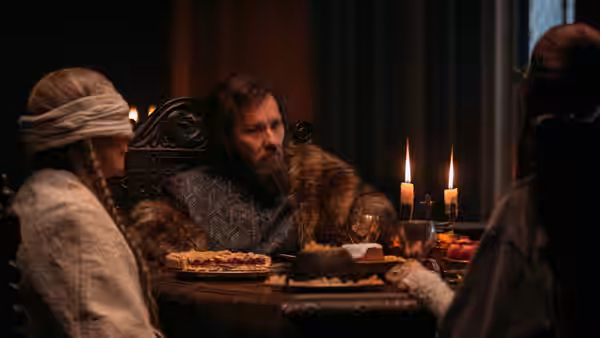 The Lord (Joel Edgerton) sits at a candlelit table with two women