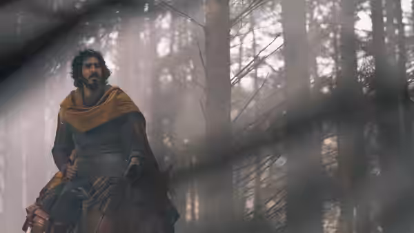 Gawain (Dev Patel) rides through a misty forest