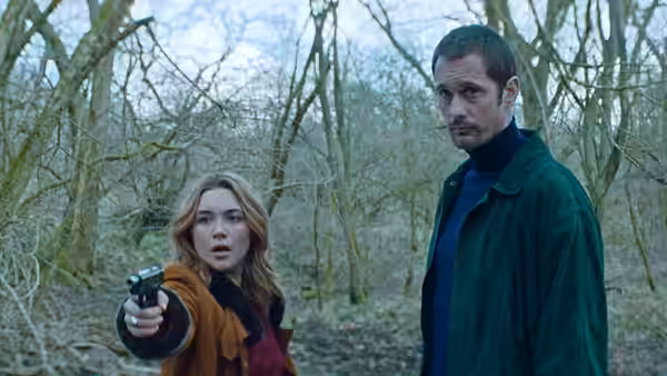 Florence Pugh as Charlie aims a gun in woods beside Alexander Skarsgård as Gadi