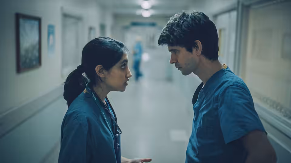 Shruti Acharya (Ambika Mod) facing Adam Kay (Ben Whishaw) in a hospital corridor