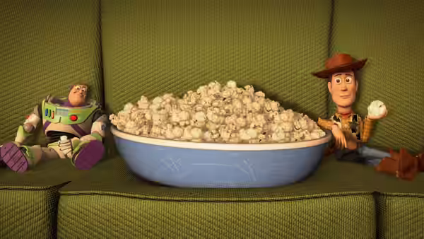 Buzz Lightyear (Tim Allen) and Woody (Tom Hanks) beside a bowl of popcorn on a couch