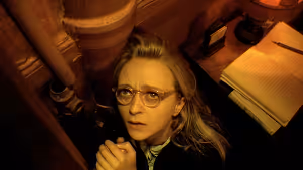 woman with glasses clasping her hands and looking upwards anxiously