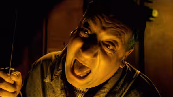 man holding a wire and yelling with wide eyes in dim light