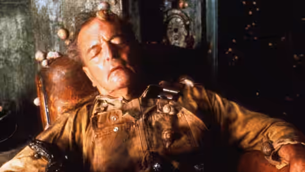 man slumped unconscious in a chair covered in small round objects