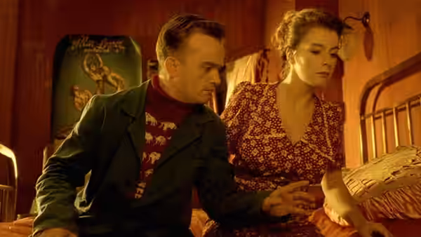 man and woman sitting close together on a bed in a wooden room