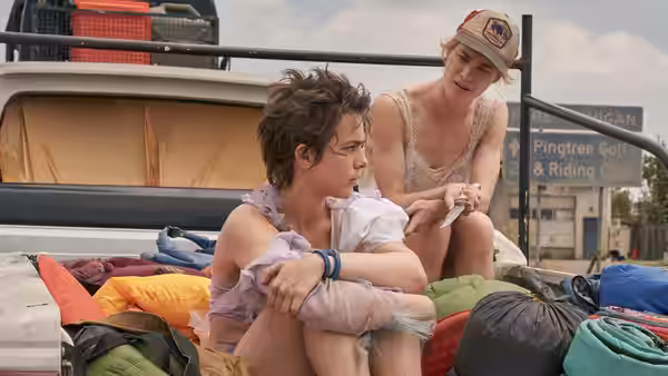 Two young people rest in the open back of a pickup truck