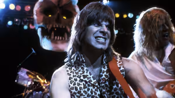Singer in leopard vest performs onstage before a large skull prop