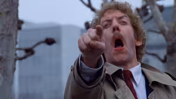 Matthew Bennell (Donald Sutherland) pointing forward with mouth open
