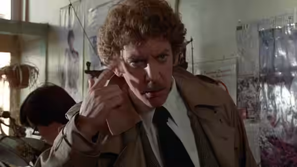 Matthew Bennell (Donald Sutherland) pointing to his temple with concern