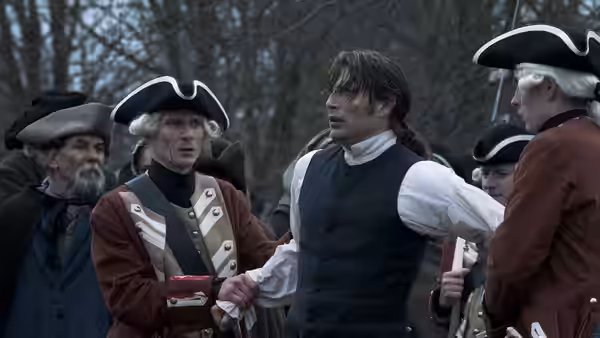 Johann Friedrich Struensee (Mads Mikkelsen) is restrained by uniformed soldiers in a forest