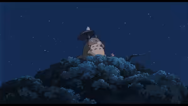 Totoro and a small creature atop a hill under the night sky