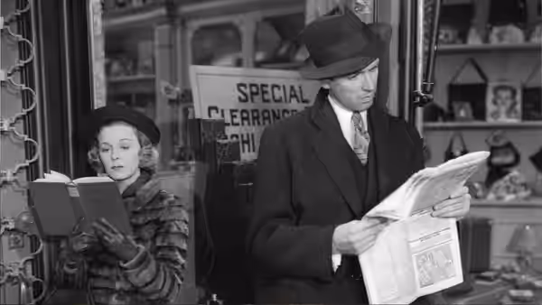 Klara Novak (Margaret Sullavan) reads a book beside Alfred Kralik (James Stewart), who studies a newspaper