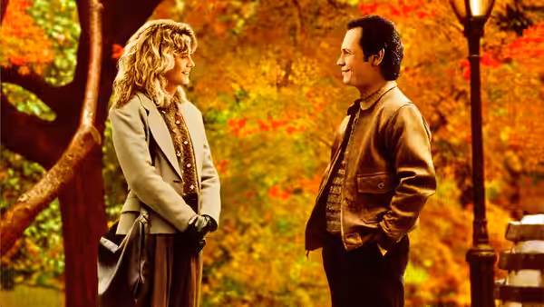 Sally (Meg Ryan) and Harry (Billy Crystal) smile at each other among fall trees