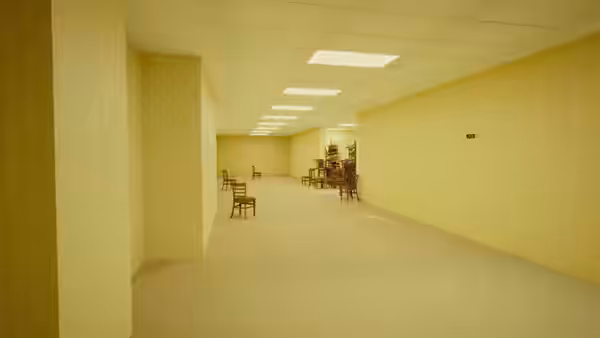 a long empty yellow hallway with scattered chairs and furniture