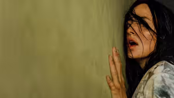 Mary (Renate Reinsve) with wet hair leaning against a green wall
