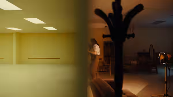 a woman in a patterned shirt standing in an empty yellow room