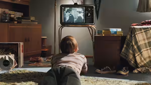 Danny Gopnik (Aaron Wolff) watching television while seated on the floor