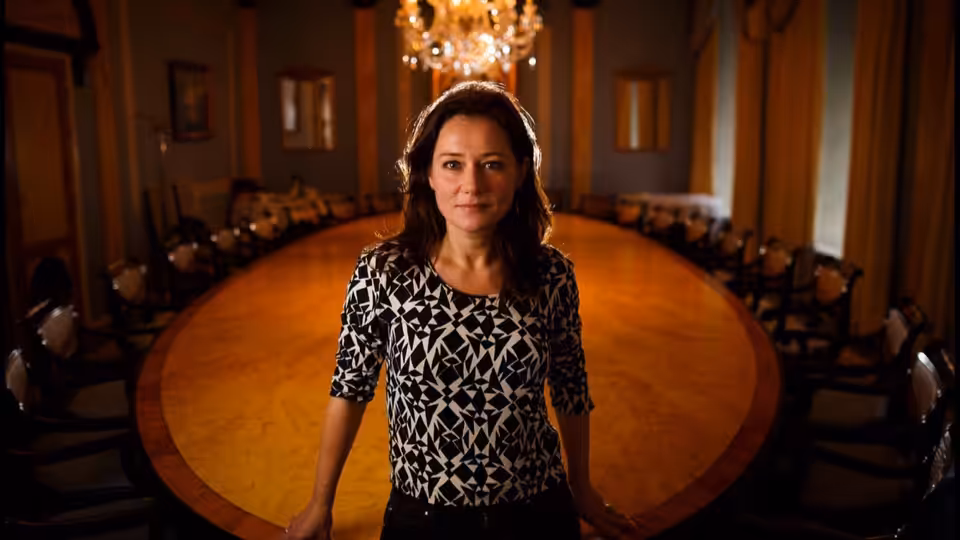 Birgitte Nyborg (Sidse Babett Knudsen) stands before a large round table