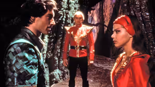 Prince Barin (Timothy Dalton) faces Princess Aura (Ornella Muti) as a red-uniformed guard watches