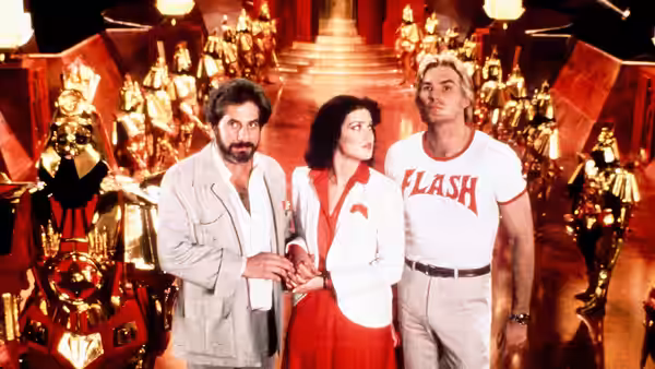 Dr. Zarkov (Chaim Topol), Dale Arden (Melody Anderson) and Flash Gordon stand among palace guards