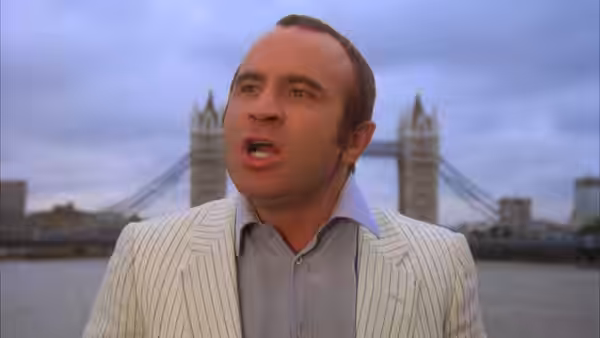 Harold Shand (Bob Hoskins) speaking in a white suit with Tower Bridge behind