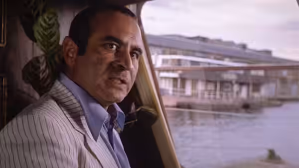 Harold Shand (Bob Hoskins) in a pinstripe suit on a boat near a pier