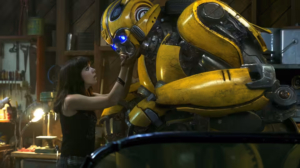 Charlie Watson (Hailee Steinfeld) reaches up to touch Bumblebee in a workshop