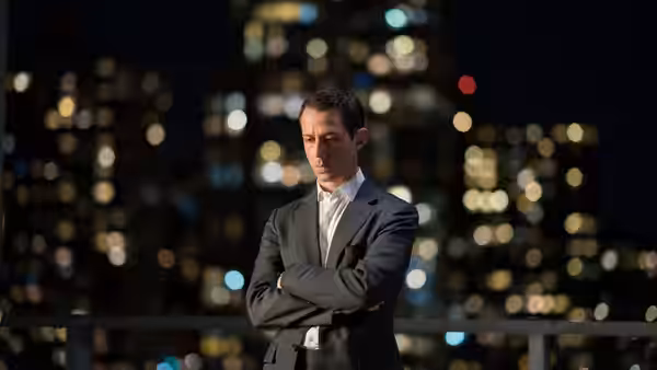 Kendall Roy (Jeremy Strong) standing with arms crossed on a balcony at night