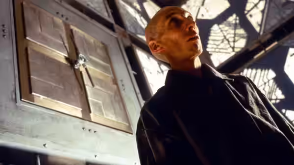 bald man gazing up at metal door in industrial setting