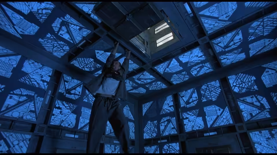 woman reaching up to ceiling hatch in blue metallic cube room